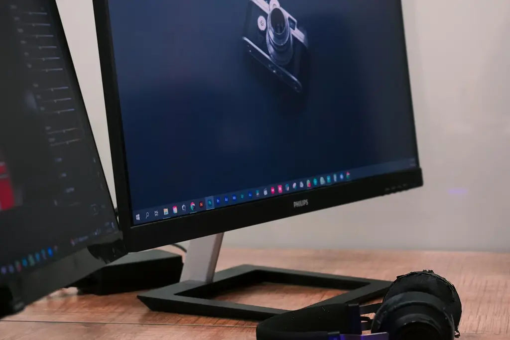 A desktop monitor on a desk beside a keyboard