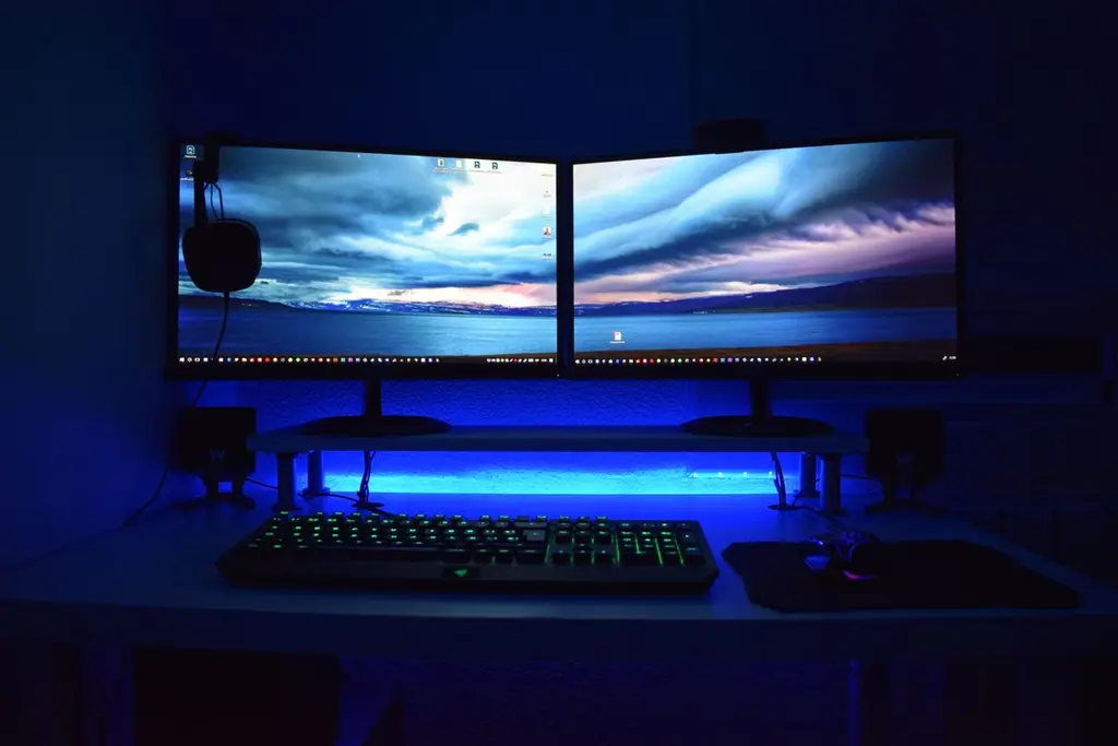 Two monitors with blue lighting on a gaming desk