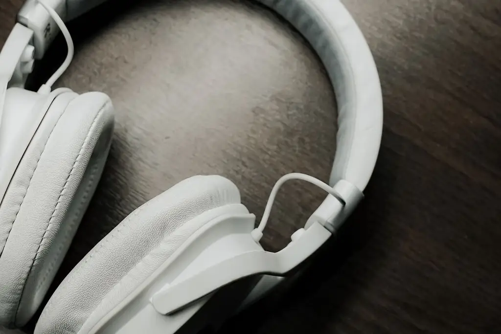 A white over-ear headset on a dark desk