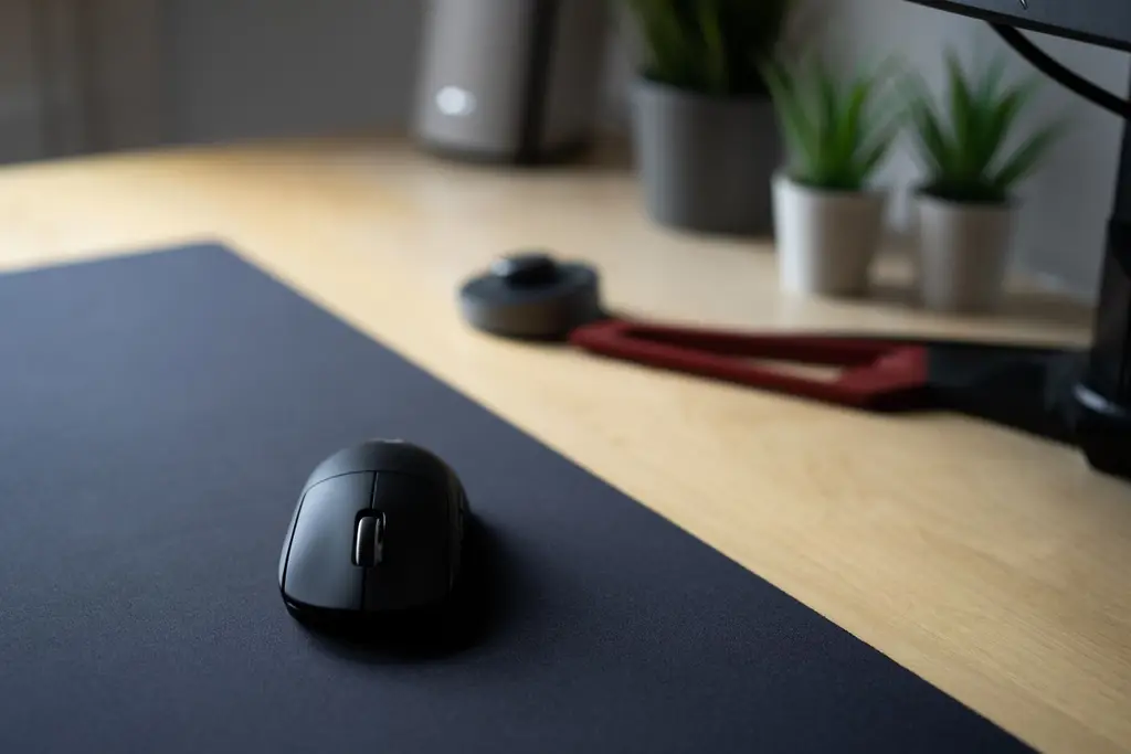 A black wireless mouse on a large black mouse pad