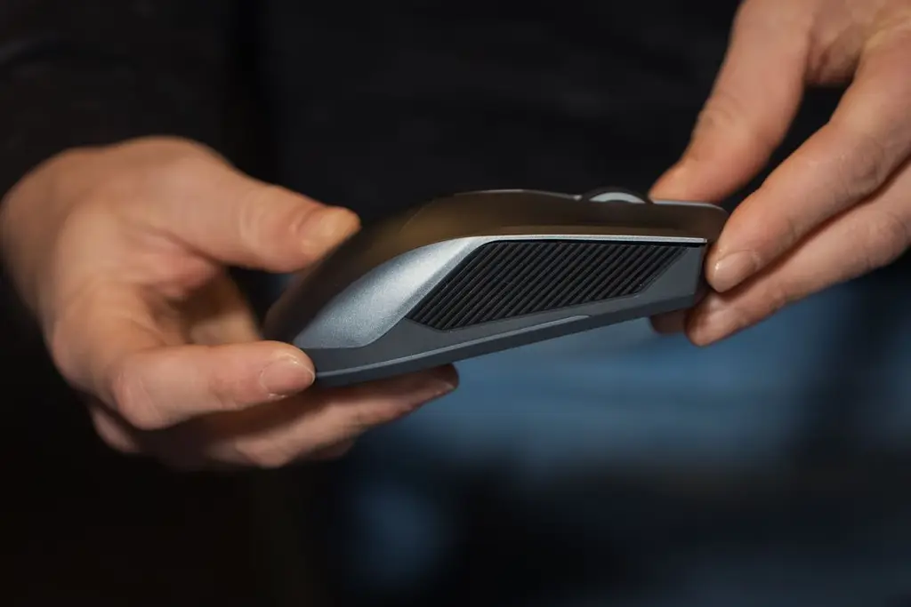 Two hands holding a silver and black gaming mouse