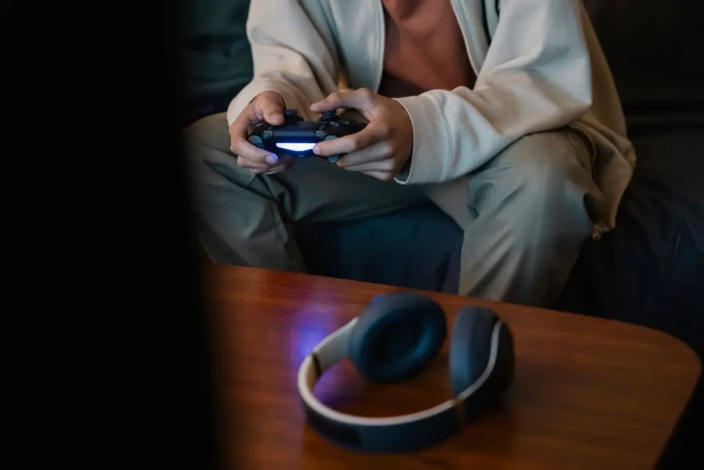 A black over-ear headset resting on a table next to a game controller