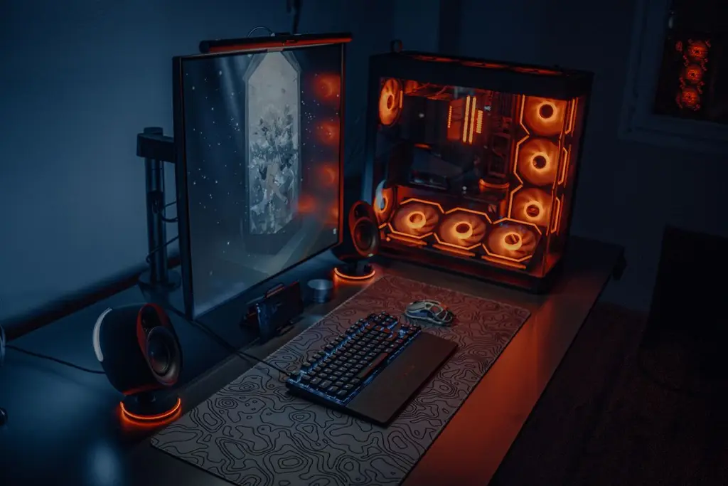 A gaming desk setup with RGB lighting, a large monitor and a keyboard