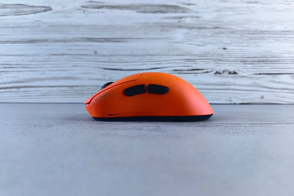 An orange gaming mouse on a grey wooden surface
