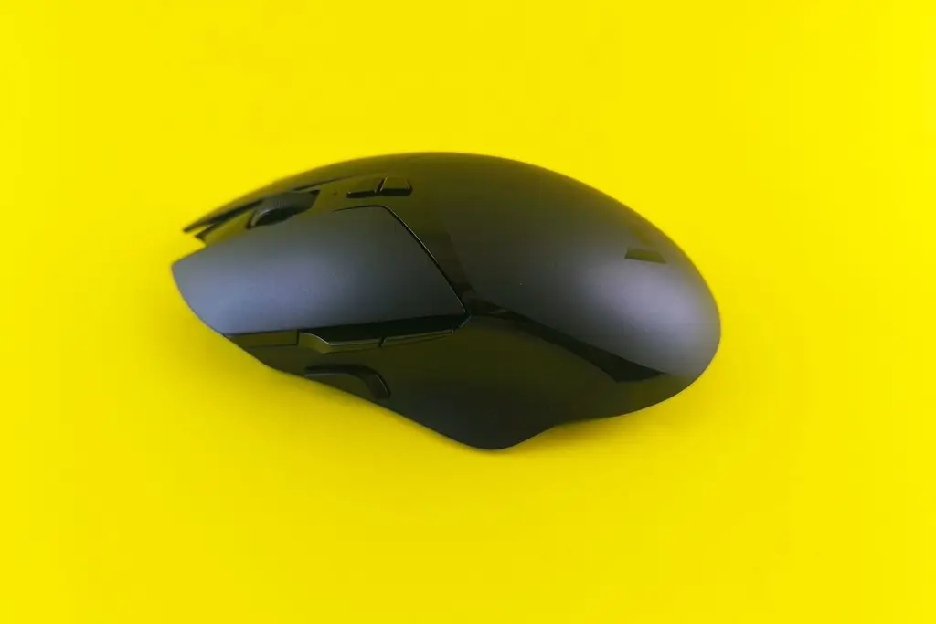A black wireless gaming mouse on a yellow background