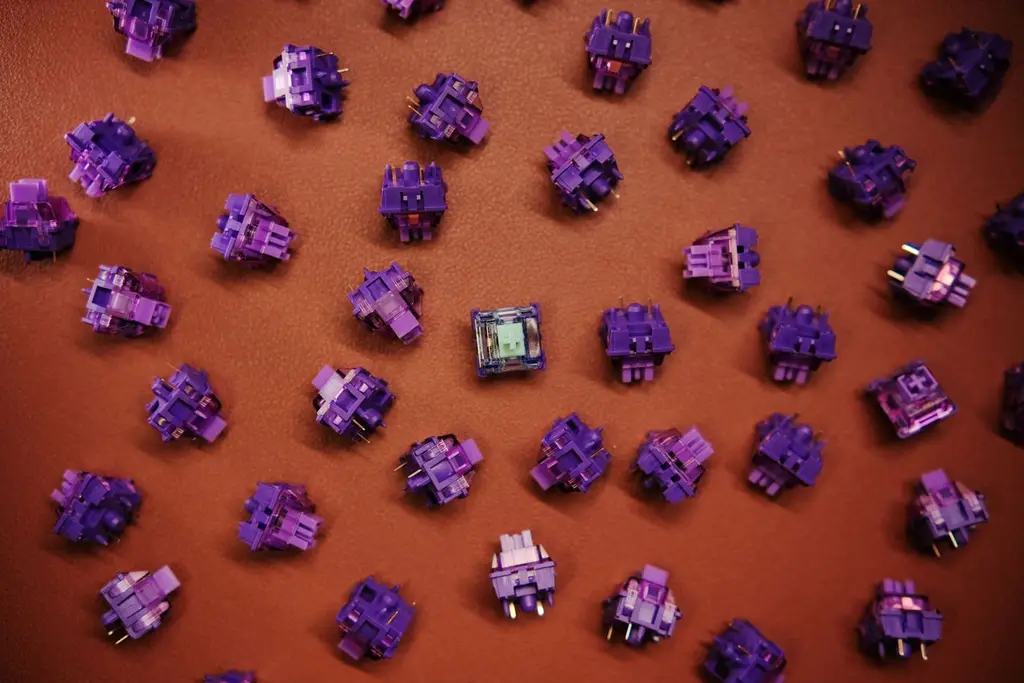 Purple mechanical keyboard switches scattered on a brown surface